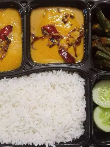 A simple yet delicious vegetarian meal featuring plain rice, dal tadka with a tempering of red chillies, crispy bhindi fry, and a side of cucumber. This is comfort food at its best.