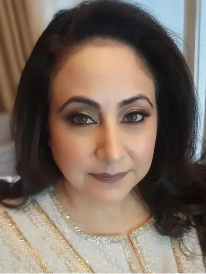 A direct, confident gaze from the client, showcasing the final, beautifully blended makeup. Her hair is left open with soft volume, completing the elegant look.