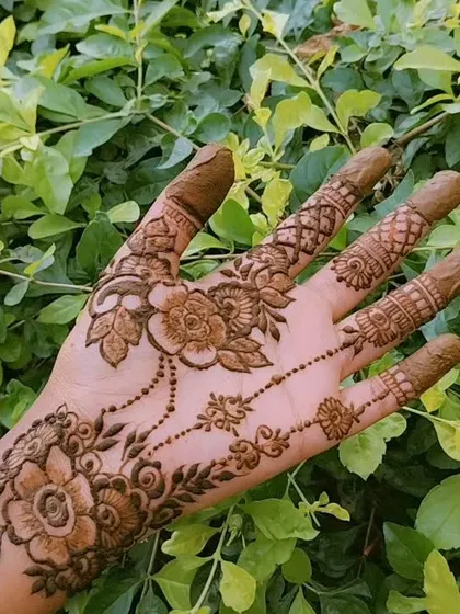 A delicate and feminine design with a floral vine that drapes across the back of the hand like jewelry. This is a perfect example of a simple yet beautiful party mehendi.