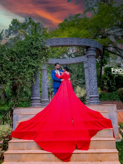 A stunning sunset shot at the stonehenge-like structure. The fiery red gown mirrors the colors of the sky, creating a powerful and romantic image that feels both epic and intimate.