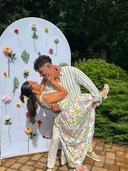A happy couple enjoying a photo opportunity in front of a beautiful floral backdrop, perfect for a bridal shower or engagement party.