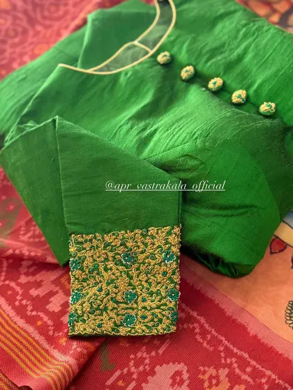 A green blouse with a button-front and embroidered cuffs.