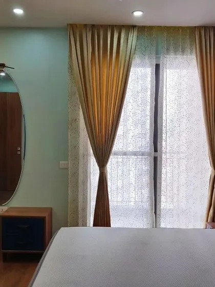 Another angle of the blue and beige bedroom, showing the elegant curtains and the oval mirror that adds a soft, modern touch.
