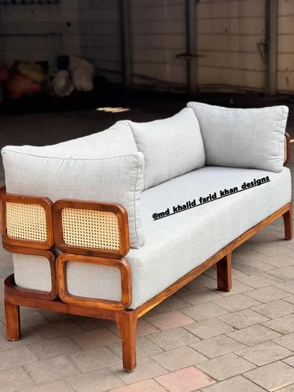 A side view of the sofa, showing the depth of the seating and the intricate details of the wood and cane frame.