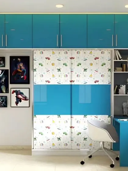A fun and functional kids' room with a blue high-gloss wardrobe. The sliding doors feature a playful car pattern, and the unit includes an attached study desk and bookshelf.
