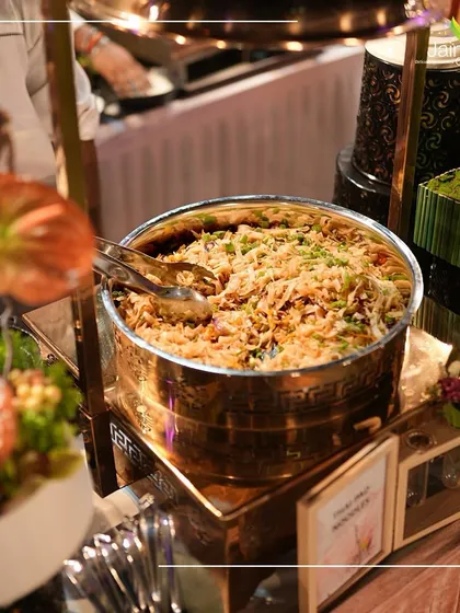 A bowl of flavorful Thai noodles or biryani, presented elegantly in a brass serving dish at Kiaraa Banquet.