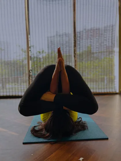 A student in a deep forward fold with a twist, showing incredible flexibility and control.