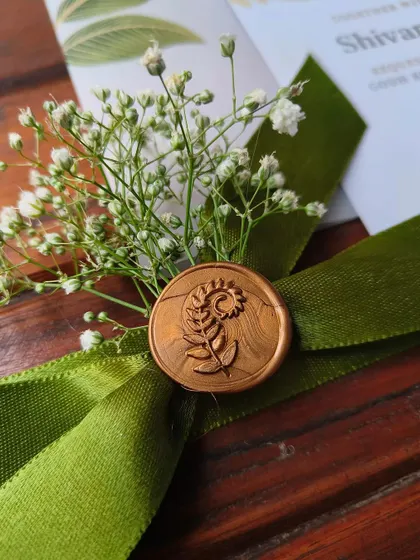 A macro shot of the custom wax seal on the S&A engagement invitation, featuring an intricate floral motif and paired with fresh baby's breath.