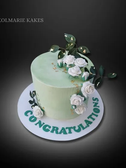 A simple and elegant engagement cake. This buttercream cake in a soft sage green is decorated with handmade white sugar roses and a touch of gold leaf for a celebratory feel.