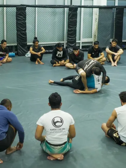 A coach demonstrating a technique to a group of attentive students. Our instruction is detailed and focused on concepts that work in competition.