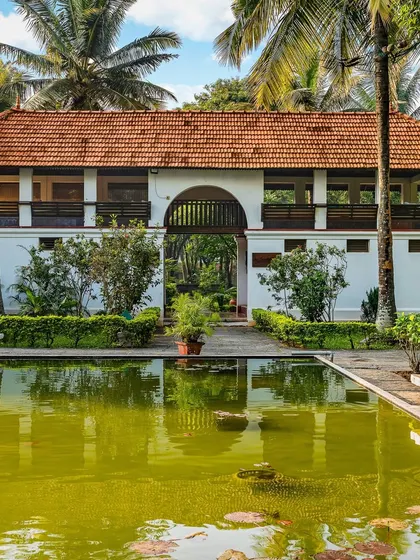 The Padipura, a beautiful Kerala heritage building, reflected in the calm waters of the pond. This tranquil space is dedicated to yoga, meditation, and quiet reflection for our guests.