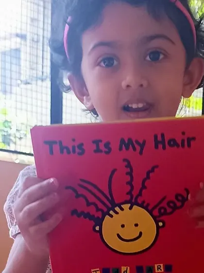 A girl proudly shows her book, "This Is My Hair."
