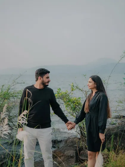 A beautiful shot of the couple holding hands and looking at each other across a natural landscape. The composition feels balanced and serene, telling a story of partnership.