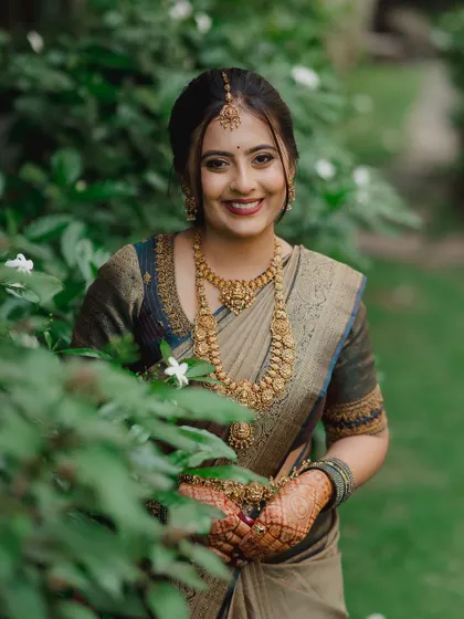A radiant bride smiling amidst lush greenery. We use natural light to create soft, beautiful portraits that capture the bride's happiness.