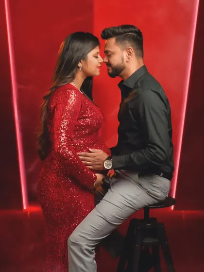 An intimate forehead-to-forehead pose, creating a powerful silhouette of connection against a vibrant red background.