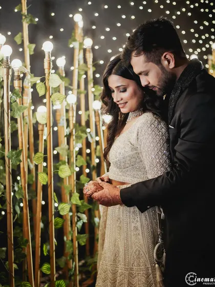 An intimate engagement photo where the couple is framed by a wall of lights and ivy, creating a secret garden feel.