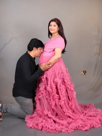A sweet interaction between the expecting parents. The dad-to-be kneels to kiss the baby bump, a classic pose that always results in a heartfelt and emotional photograph.