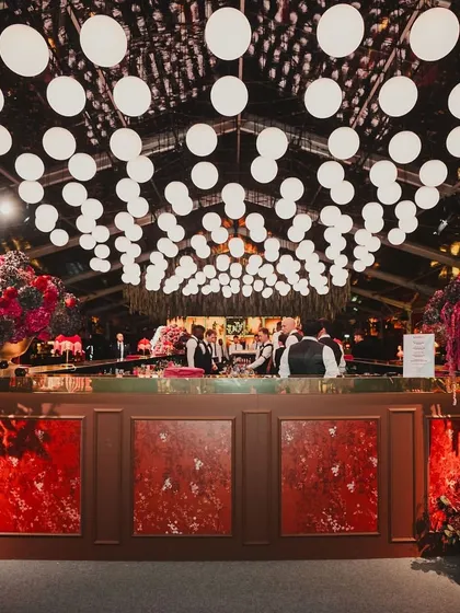 A look inside a glamorous red and maroon themed cocktail night, with velvet textures, a custom poker theme, and a stunning floral-decked bar.