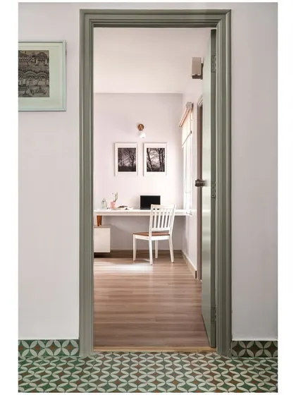 A view from a hallway with patterned cement tiles, looking into a clean, minimalist study room.