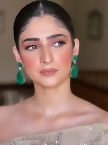 A close-up of a soft, peachy-pink makeup look with a sleek bun. This is a perfect example of elegant party makeup.