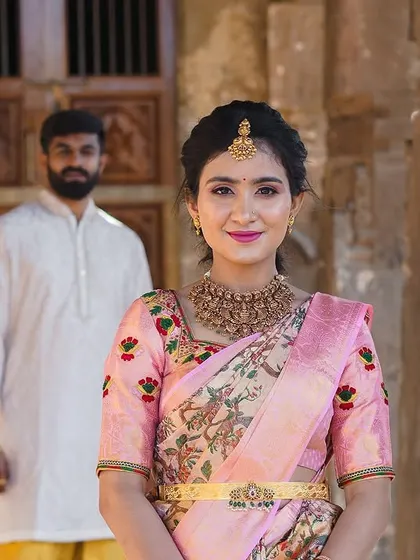This bride is styled for a pre-wedding shoot with a traditional theme. The saree draping is classic, and the simple hairstyle allows the focus to be on her and the beautiful heritage location.