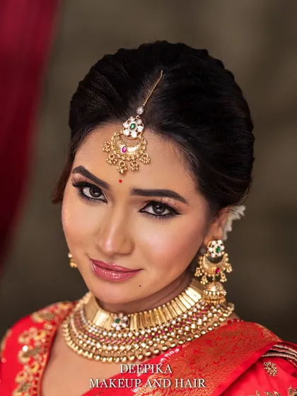 A close-up of the bride's face, showing off the winged eyeliner and the traditional gold jewelry. Her expression is serene and confident.