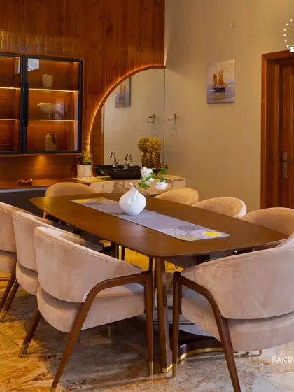 An elegant dining space with a warm, inviting feel. The wooden dining table, plush chairs, and integrated wash basin with a curved mirror combine practicality with sophisticated design.