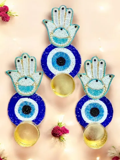 Hand-beaded evil eye and Hamsa hand wall hangings that double as diya holders. These are perfect as unique return gifts or as part of a larger traditional hamper.