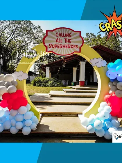 A grand circular entrance arch "Calling All The Superheroes," decorated with balloons in classic hero colors, ready to welcome guests to an epic adventure.