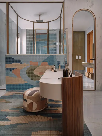 The master bathroom at Rehethaan is a symphony of color and texture. A custom mosaic rug on the floor mirrors the abstract, watercolor-like patterns of the mosaic tiles on the wall.
