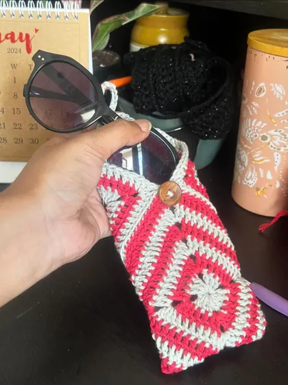 Holding the granny square pouch to show its size. It’s a great way to use a classic crochet pattern for something modern and useful.