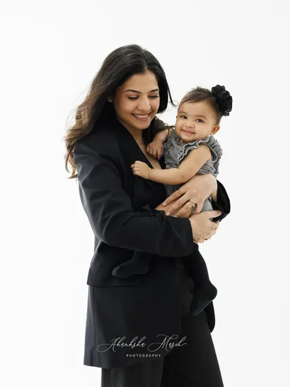 A sweet moment captured between a mother and her baby. The baby's happy smile over her mother's shoulder is simply adorable.