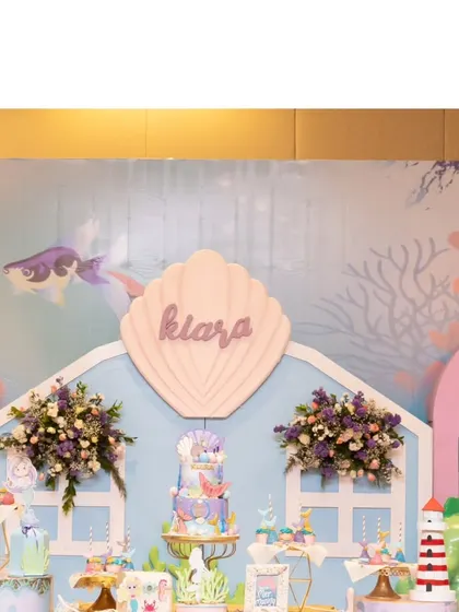 The main stage for Kiara's mermaid party, featuring a large shell with her name. The backdrop is designed to look like an underwater castle, creating a perfect setting for a little princess.