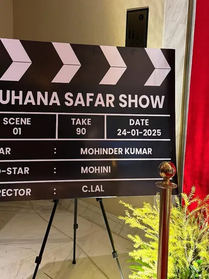 A personalized film clapperboard prop for the "Suhana Safar Show," celebrating a 90th birthday. Custom details like this make the guest of honor the star of the show.