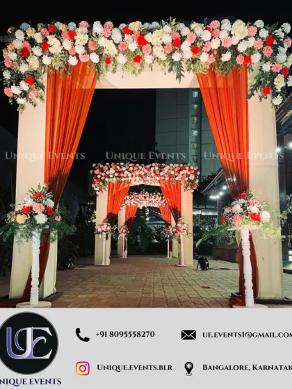 The first impression matters. We designed this grand floral entrance archway with warm-toned draping to create an inviting and luxurious welcome for guests arriving at this nighttime wedding celebration.