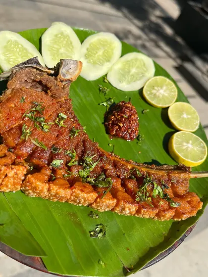 Another view of our popular crispy pork ribs, presented on a banana leaf to highlight the authentic Naga style of serving food. The dish is garnished with cilantro and served with our fiery chili chutney.