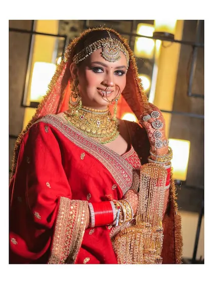 A classic and radiant portrait of a Sikh bride. Her traditional red outfit, golden jewelry, and bright smile are perfectly captured.