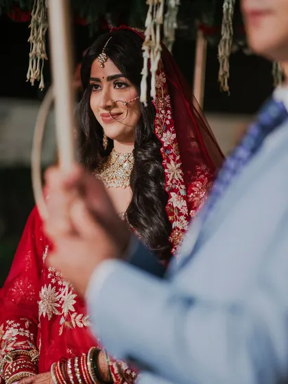A close-up of the bride, Anisha, during her phoolon ki chadar entry. Her serene expression and beautiful red attire are the focus of this emotional shot.