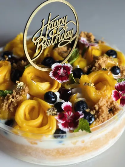 A stunning mango and blueberry birthday cake. The combination of sweet mango roses, fresh blueberries, and edible flowers makes this a true summer showstopper.