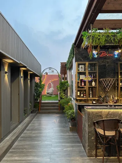 This image shows the seamless flow from an indoor corridor to the outdoor bar area we designed. The consistent use of greenery and modern materials creates a cohesive and inviting journey for guests.