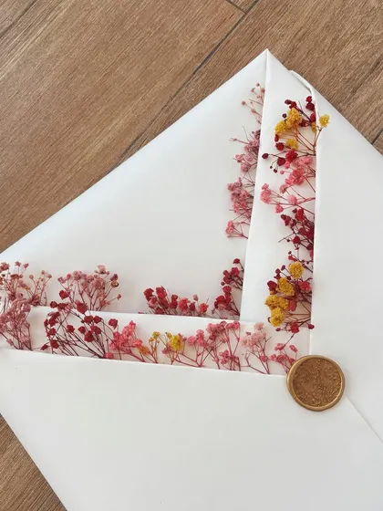 A classic wrap with a twist. This ivory paper wrap, filled with dried flowers peeking out from the folds and sealed with a golden wax stamp, is the perfect way to present a framed handwritten letter.