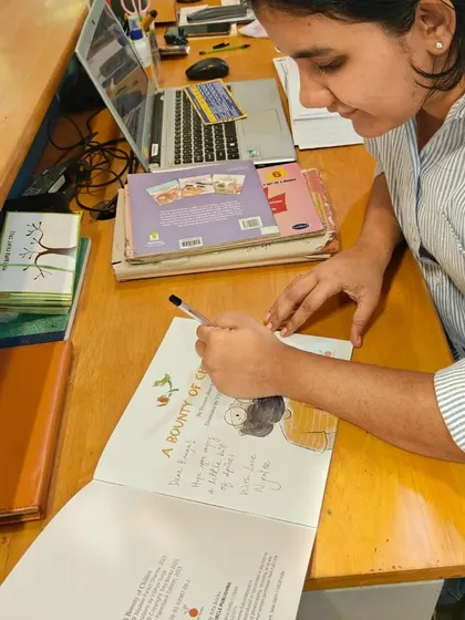 A close-up of illustrator Vibha Surya signing a copy of 'A Bounty of Chilies' with a custom drawing.