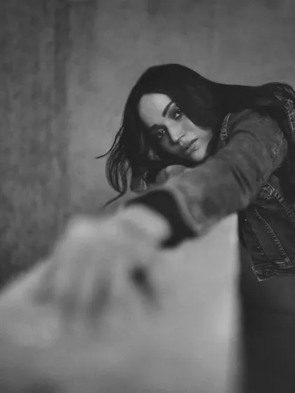 An artistic shot that uses foreground blur to draw the viewer's eye to the subject's face, creating a sense of depth and longing.