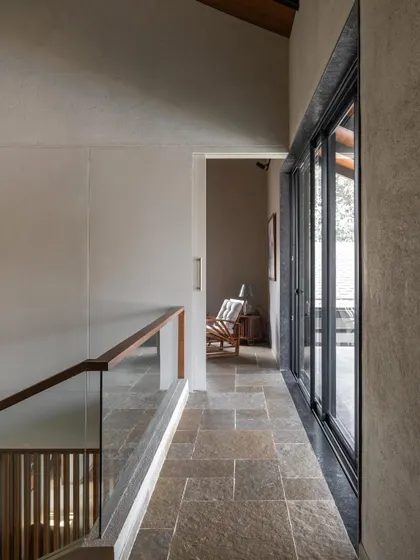 The upstairs corridor at Grove House, with its stone floor and glass railing, overlooks the garden below.