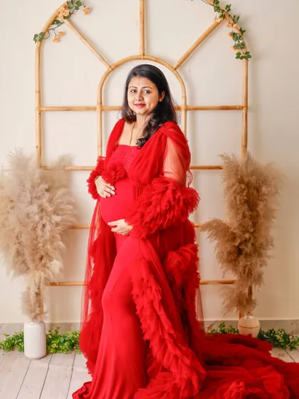 A lovely portrait in a red ruffled gown, posed in our studio's boho window set, complete with pampas grass and greenery.