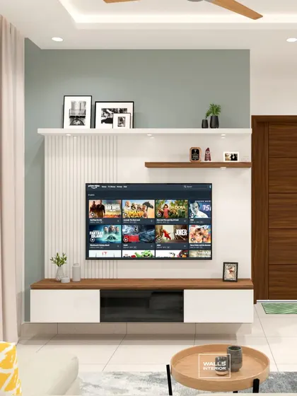 A floating TV console in white and wood is mounted against a wall with white vertical fluting and a soft green accent. This minimalist design provides storage while keeping the living room feeling spacious.