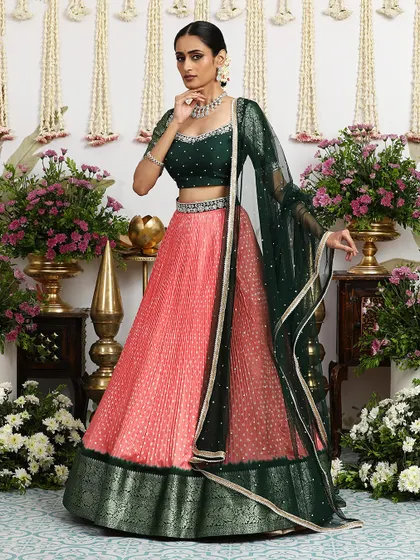 The flowing green dupatta adds a touch of drama to the coral pink lehenga.