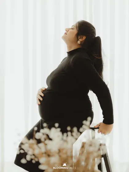 A serene and contemplative silhouette in a black turtleneck dress. This shot beautifully captures the quiet strength of motherhood.