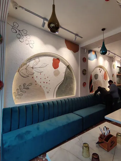 A wider view of the Boho-themed murals at Cafe Berni, showing how the art in the arches and on the surrounding walls creates a cohesive and stylish interior.