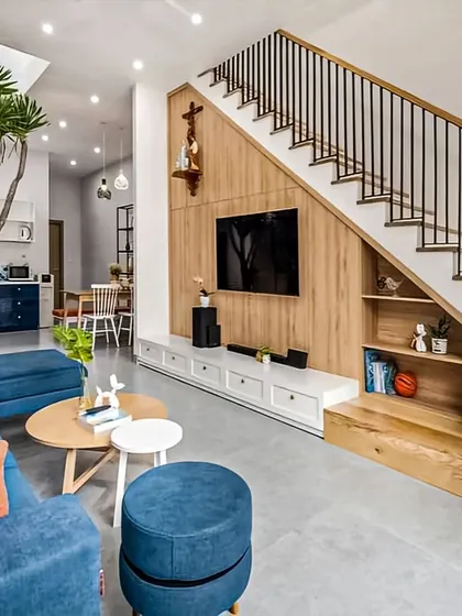 We maximized space in this living room by building a custom TV unit under the staircase. This solution includes open shelves for decor and closed cabinets for storage, turning an awkward area into a functional feature.